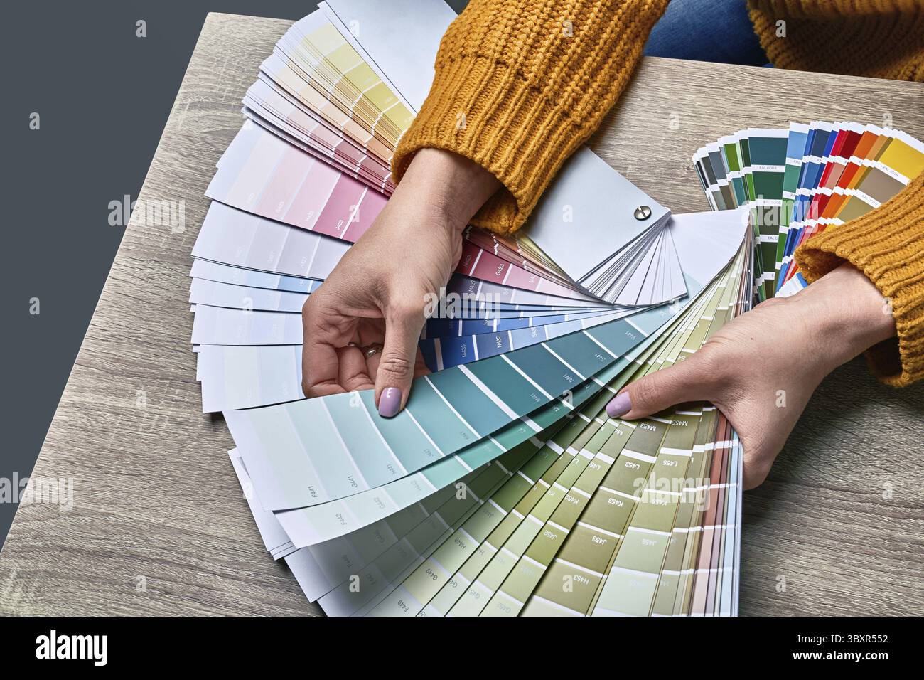 Ruota dei colori per la scelta del tono di vernice. Mani di una designer di interni che lavora con la tavolozza per scegliere i colori. Concetto di processo creativo. Confronto di o Foto Stock