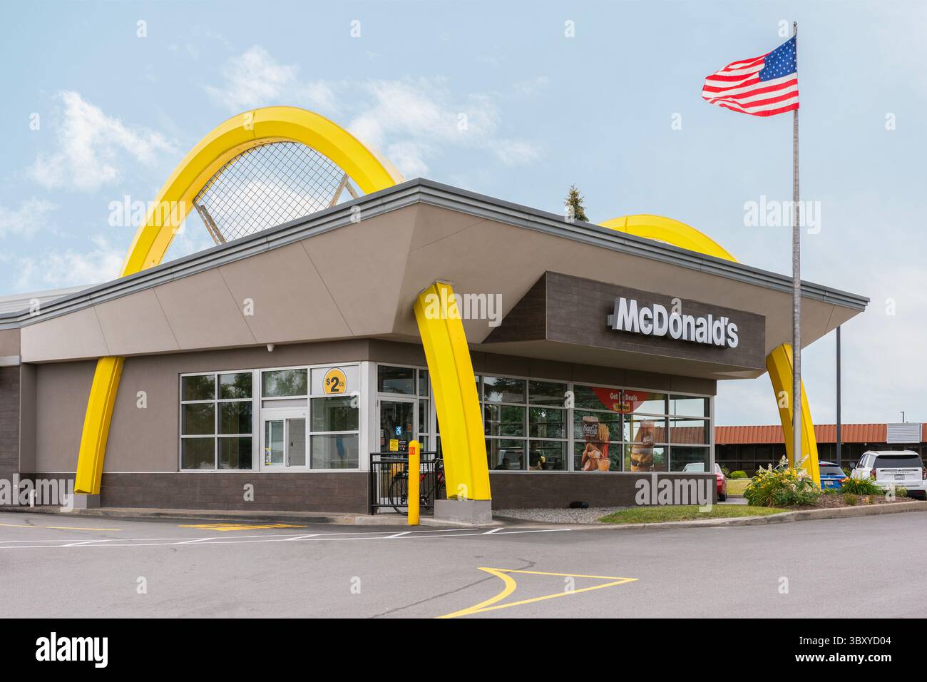 Utica, NY - 8 luglio 2025: Ampia vista serale del ristorante McDonald's con la bandiera degli Stati Uniti, fondato nel 1940, è una delle più grandi catene di fast food del mondo, Foto Stock