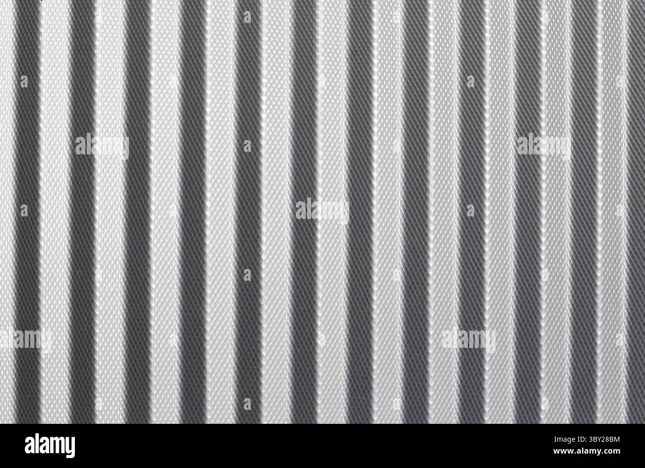 Texture astratta a righe verticali dal look metallizzato. Primo piano della superficie ondulata in tonalità bianche e grigie. Linee ripetute e ripetizione d'ombra. Foto Stock