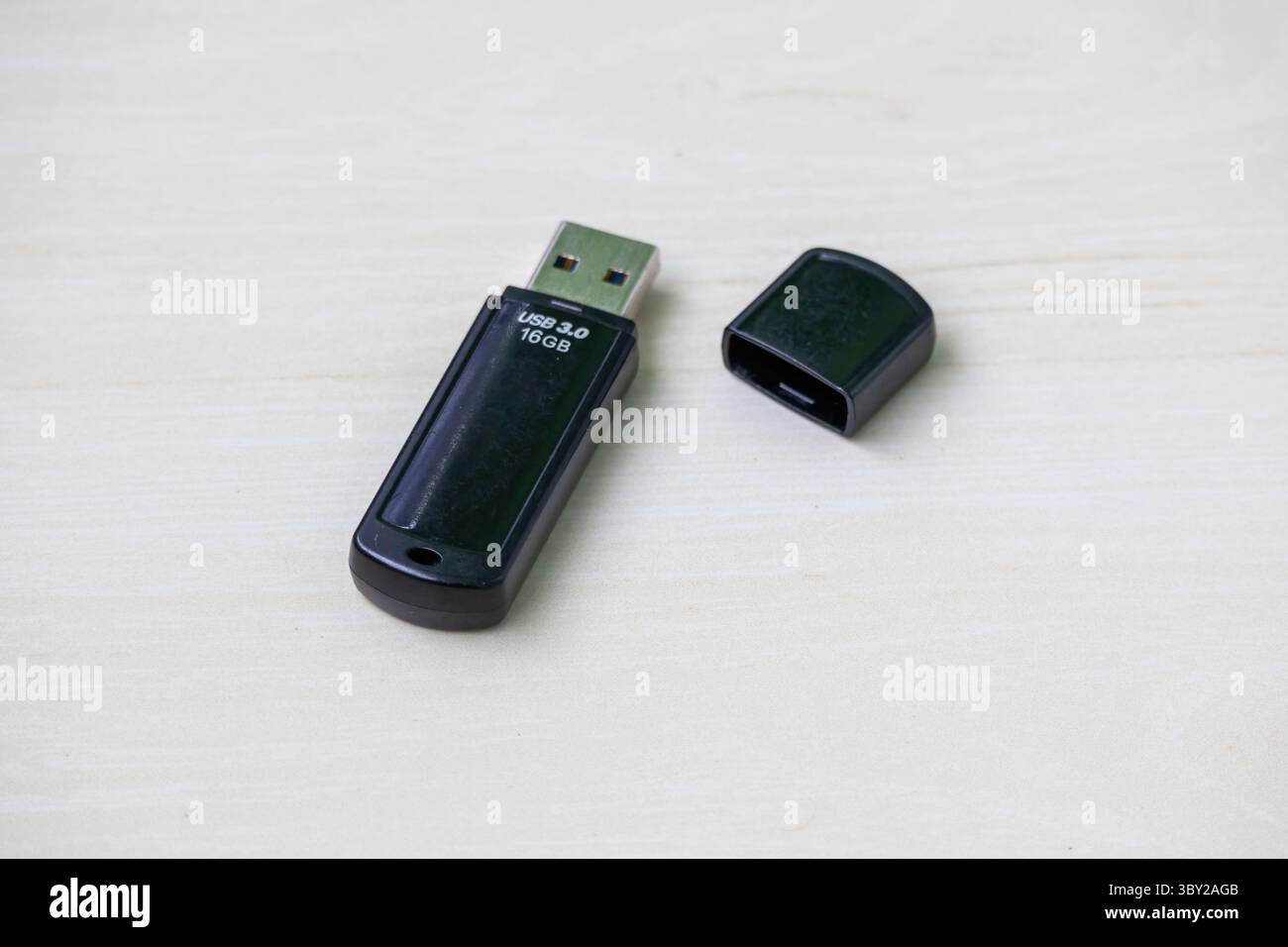 Pendrive USB 3,0 nera ad alta velocità da 16 GB su sfondo in legno chiaro, perfetta per temi tecnologici, di memoria e di ufficio. Foto Stock