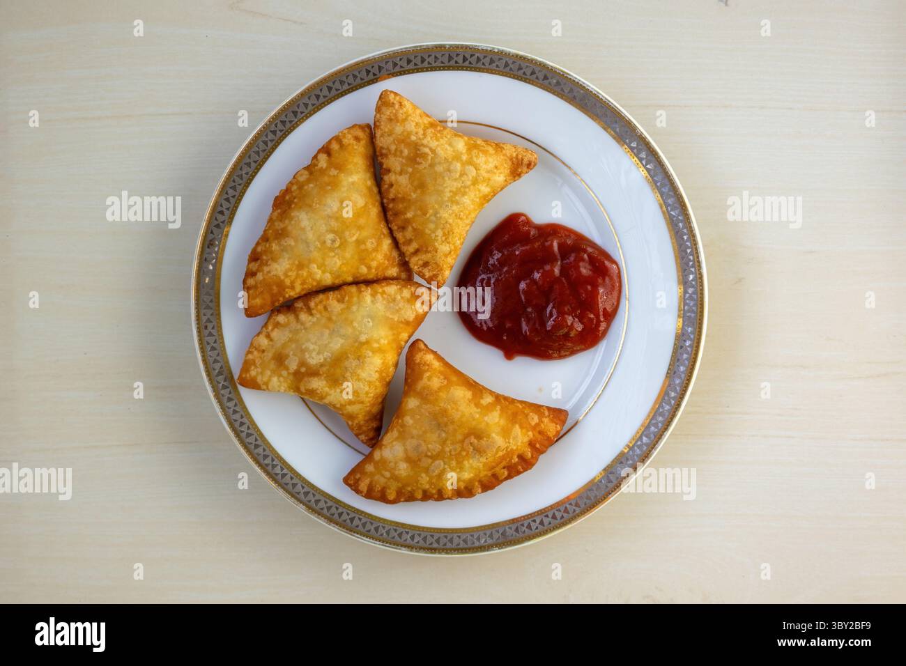 Vista dall'alto di deliziosi samosa di manzo e salsa di pomodoro su un piatto. Questo popolare spuntino dell'Asia meridionale, conosciuto come samsa, sambosa, sambusak e samoosa, è una t Foto Stock