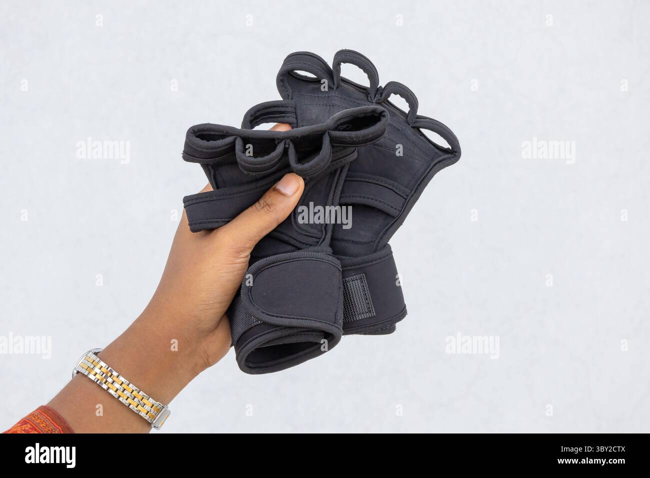Mano femminile che tiene guanti da palestra neri con supporto per il polso. Perfetto per allenamenti in palestra, pull-up e fitness, offre la massima protezione delle mani e Foto Stock