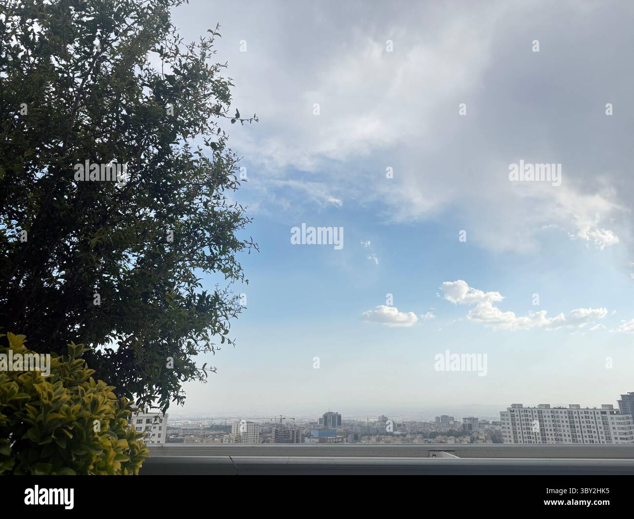 Una vista grandangolare dello skyline di Teheran sotto un cielo vibrante al crepuscolo, che mostra la silhouette urbana della città e la luce naturale soffusa. - Immagine stock catturata con smartphone