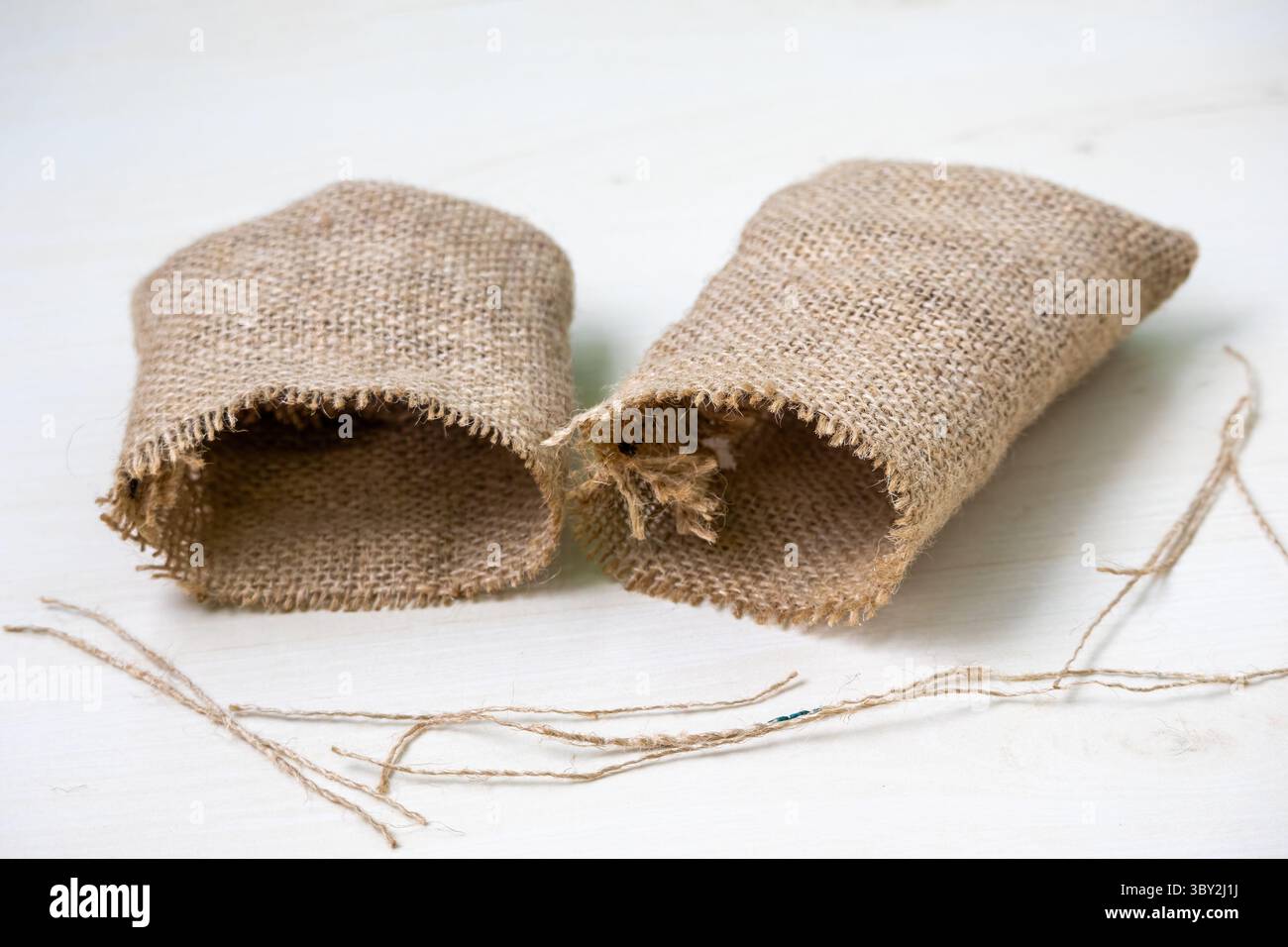 Piccoli sacchetti di iuta marrone vuoti su sfondo bianco. Sacchi tessili isolati, imballaggi naturali, stoccaggio rustico, agricoltura, ecocompatibilità. Perfetto per i professionisti Foto Stock