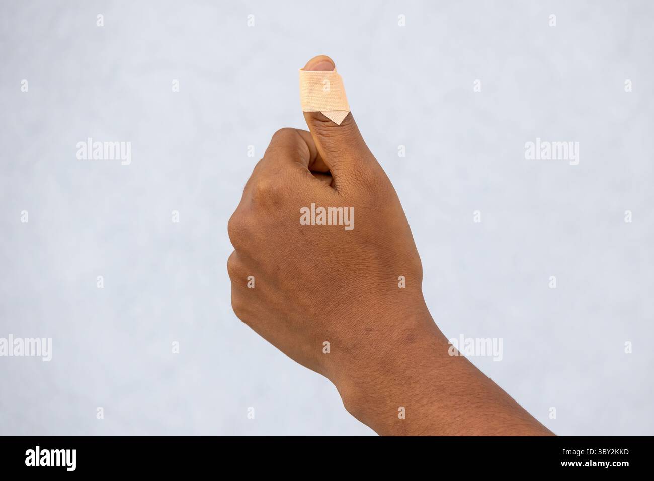 Primo piano con dito del pollice femminile ferito, tagliato con un coltello, con una benda adesiva applicata. Concentrati sull'intonaco sulla mano ferita, showi Foto Stock