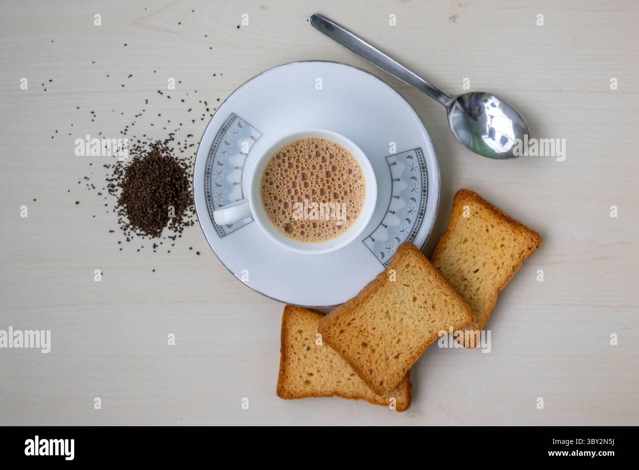 Tè al latte caldo con schiuma e croccanti croccanti croccanti croccanti. Foglie di tè fresche e secche su fondo di legno. Vista dall'alto perfetta per blog di cibo e bevande Foto Stock