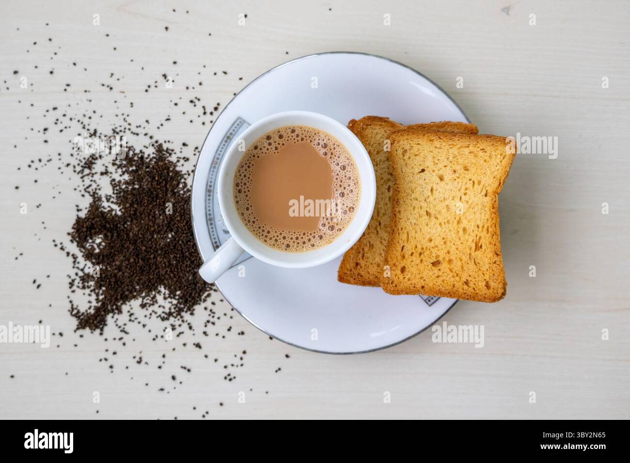 Tè al latte caldo con bollicine in un teacup e croccanti croccanti croccanti croccanti al crespo. Foglie di tè fresche e secche su fondo di legno. Questa deliziosa bevanda è anche conosciuta Foto Stock
