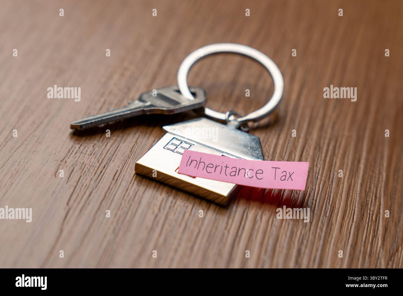 Un portachiavi a forma di casa con una chiave e una nota "imposta sull'eredità". Proprietà, eredità e concetto di tassazione associato. Foto Stock