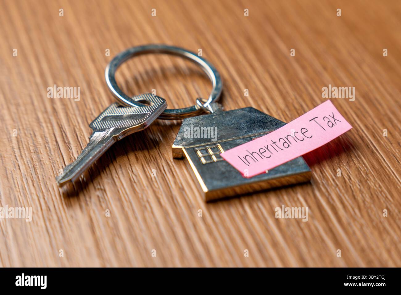 Un portachiavi a forma di casa con una chiave e una nota "imposta sull'eredità". Proprietà, eredità e concetto di tassazione associato. Foto Stock