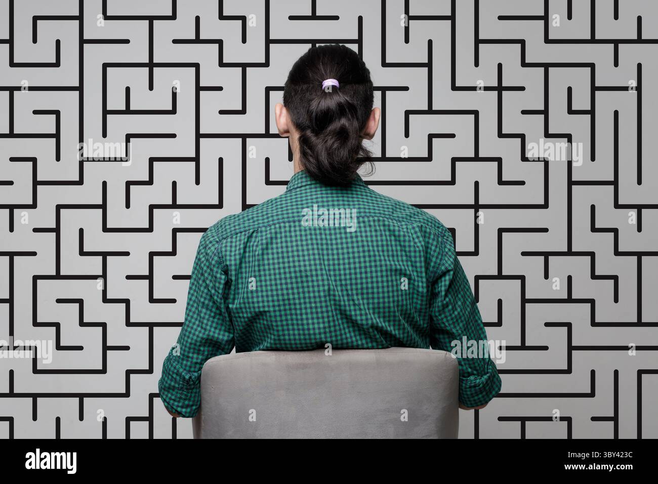 Una donna è in piedi vicino a un muro con un disegno di un labirinto. Concetto di brainstorming, pensiero, risoluzione dei problemi Foto Stock