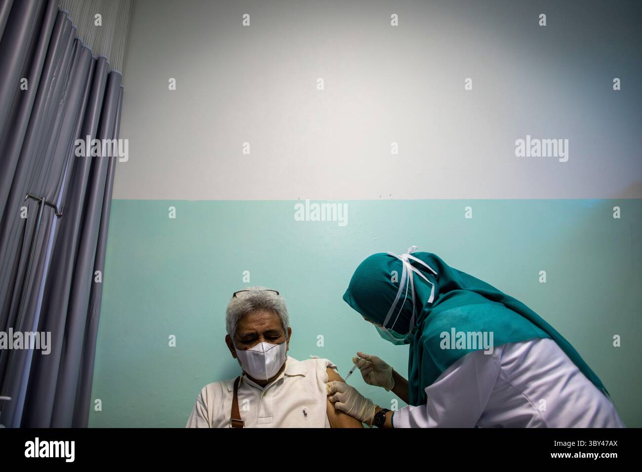 24 gennaio 2022, Tangerang Selatan, Banten, Indonesia: Un uomo chiude gli occhi mentre riceve un'iniezione di richiamo per il vaccino COVID-19, durante l'implementazione del vaccino Covid-19 Booster per gli anziani all'ospedale South Tangerang. Il governo continua a perseguire dei promotori, soprattutto per gli anziani, per prevenire i casi di morte a causa dell'aumento della variante Omicron in Indonesia. (Immagine di credito: © Donal Husni/ZUMA Press Wire) Foto Stock