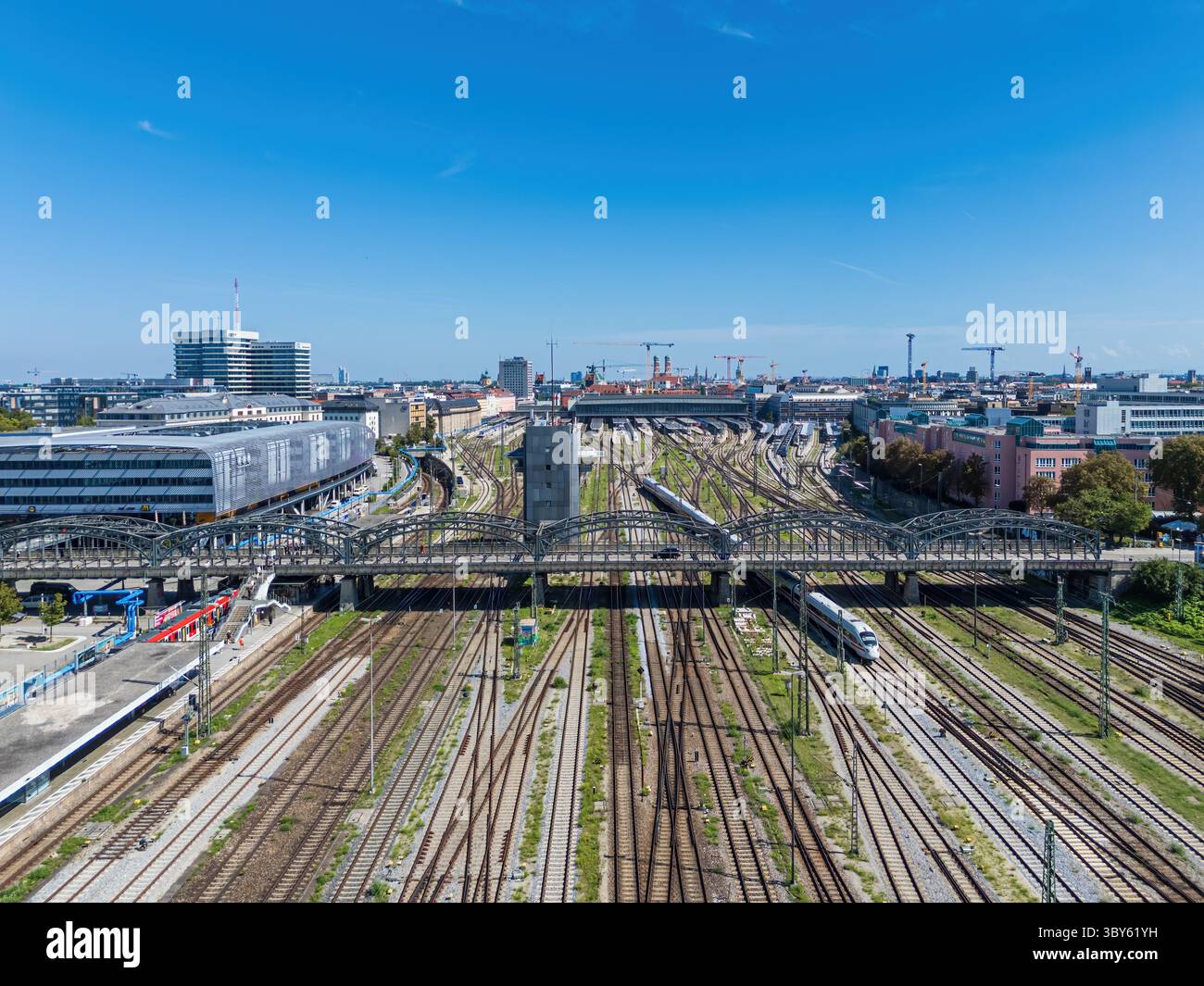 Vista aerea con droni della stazione centrale di Monaco, il principale nodo ferroviario della città, con binari ferroviari, piattaforme e architettura urbana circostante. Foto Stock