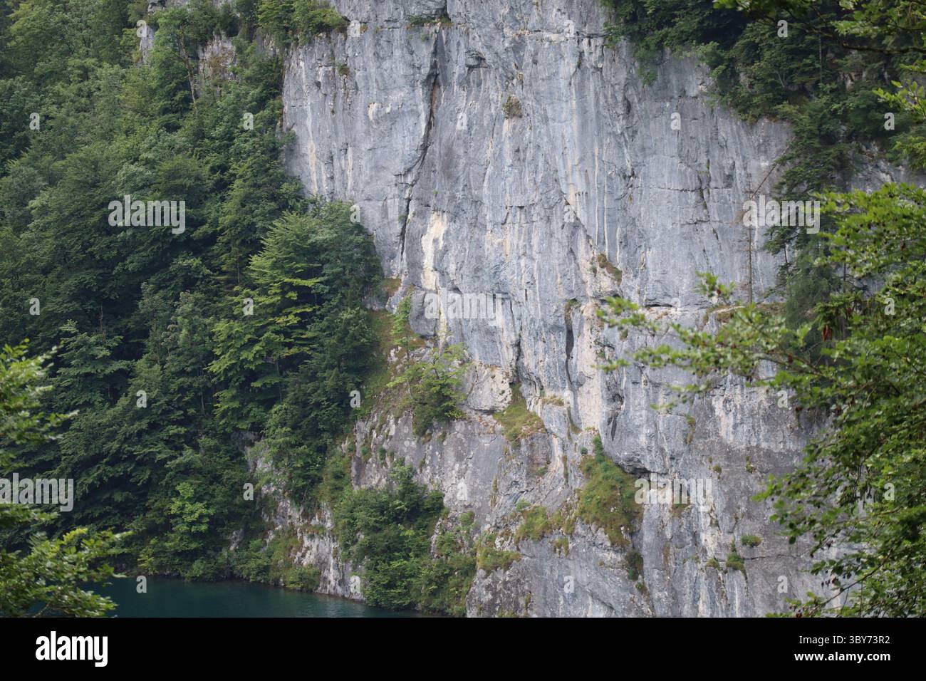 Ripida parete rocciosa di fronte a un lago Foto Stock