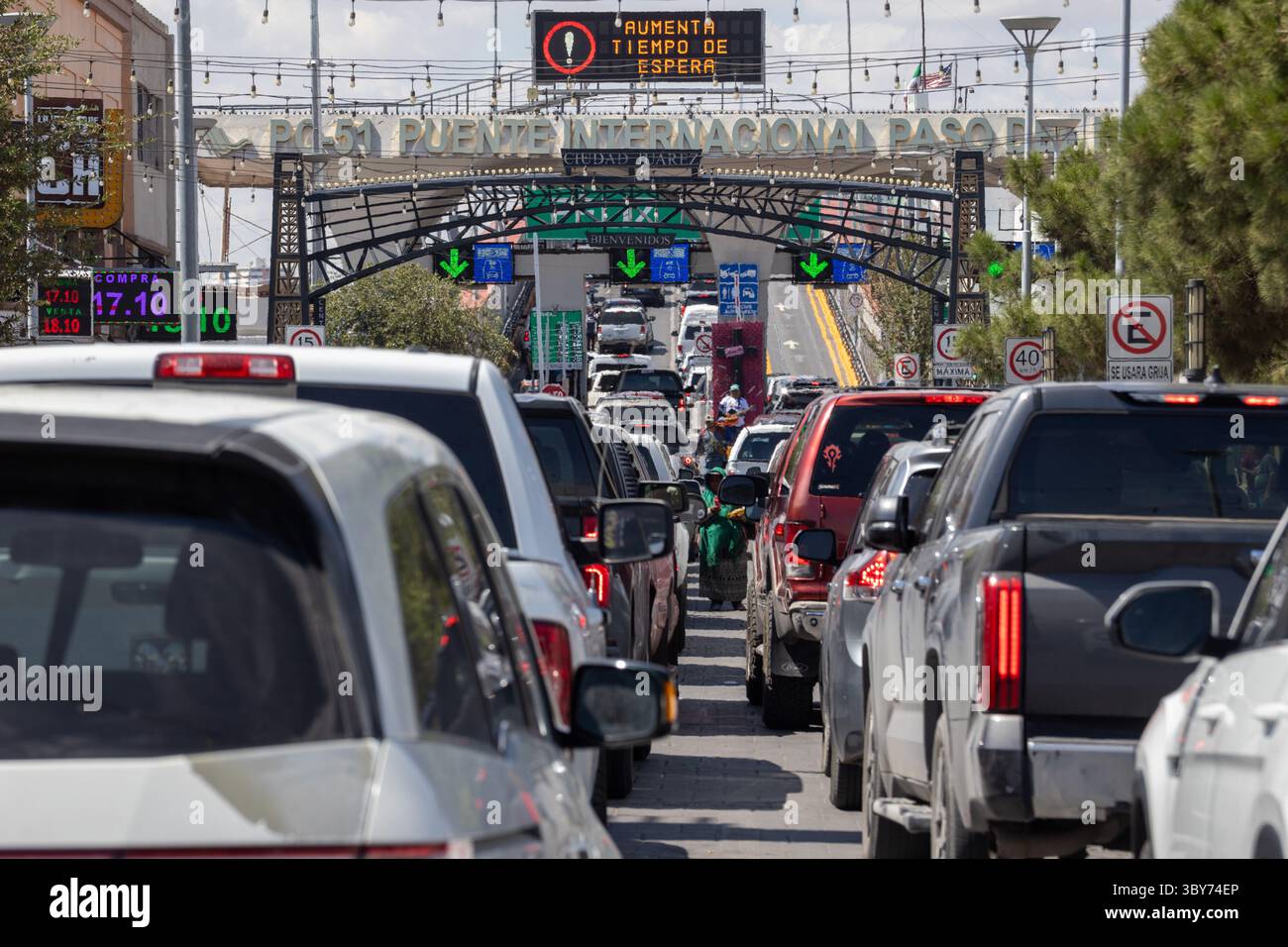 Lunghe code di veicoli al confine di Ciudad Juarez, in attesa di entrare sotto l'arco di benvenuto. Foto Stock
