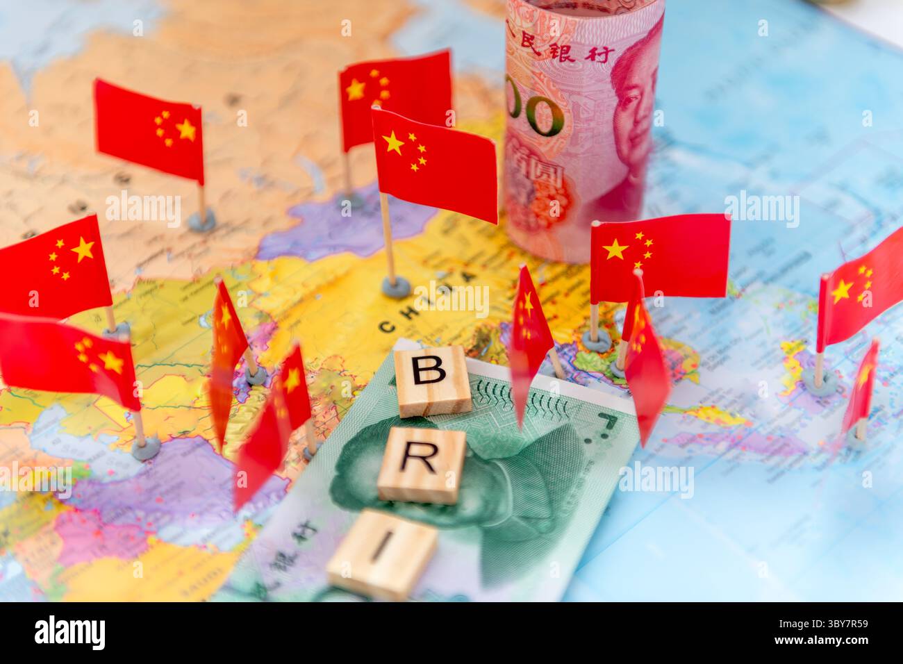 Tessere di lettere, banconote cinesi Yuan e bandiere nazionali su una mappa di parole. Un concetto di iniziativa su nastro e strada. Foto Stock