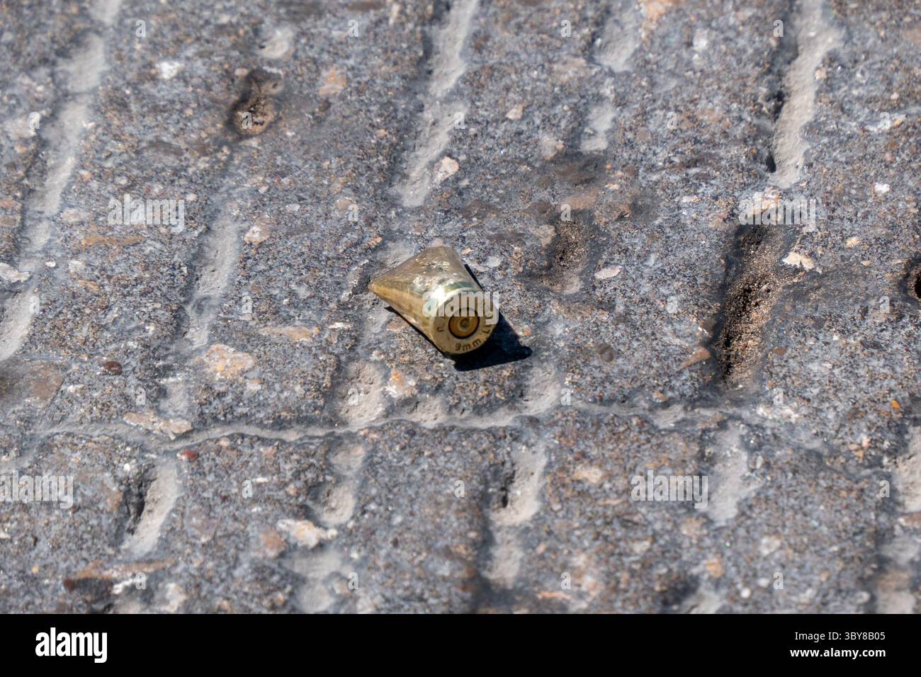 Un involucro di proiettile solitario su un terreno sassoso, che riecheggia la dilagante violenza urbana di Ciudad Juarez. Foto Stock
