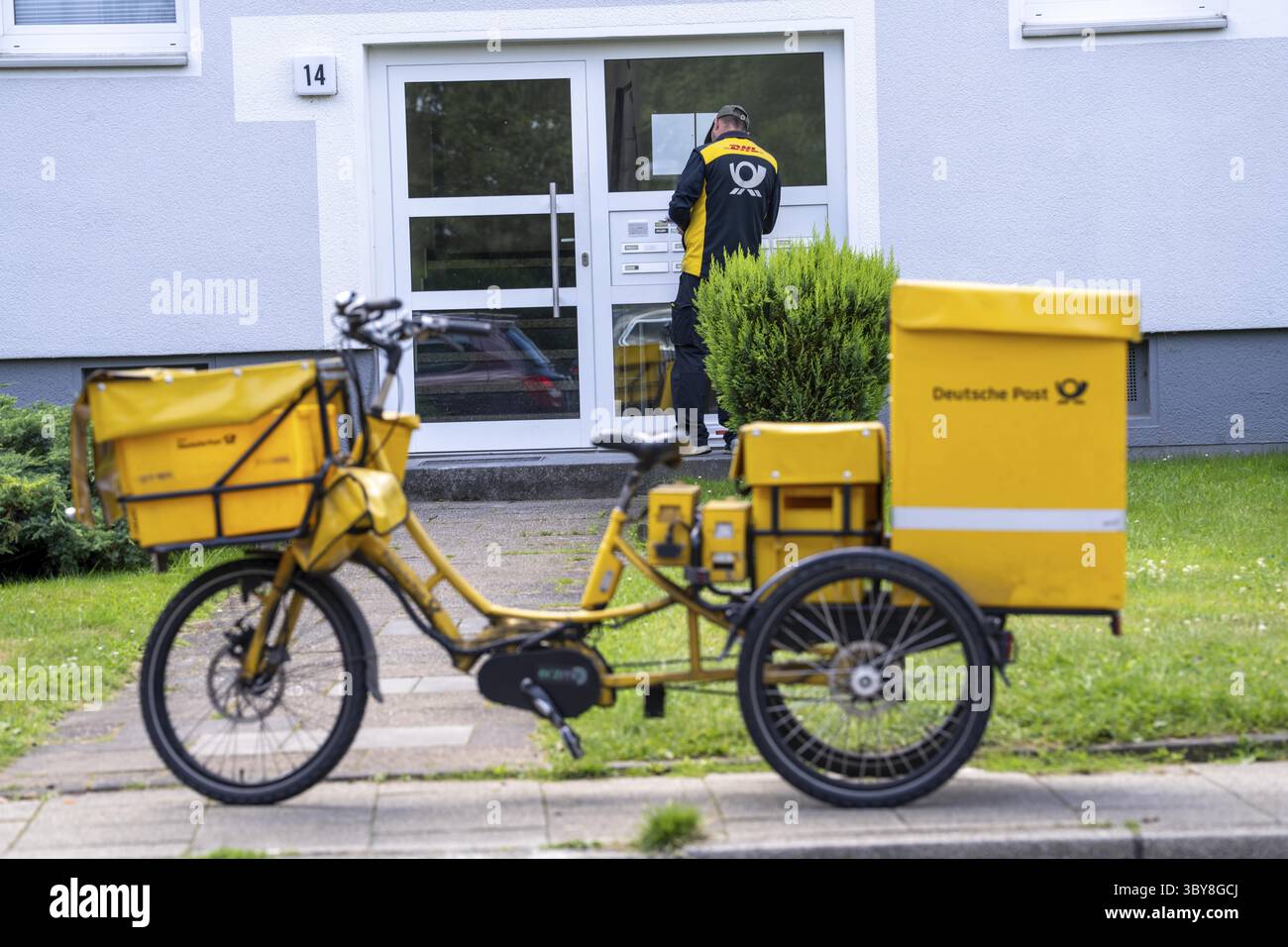Postman, Deutsche Post, distribuisce la posta in un condominio, triciclo elettrico, Renania settentrionale-Vestfalia, Germania Foto Stock