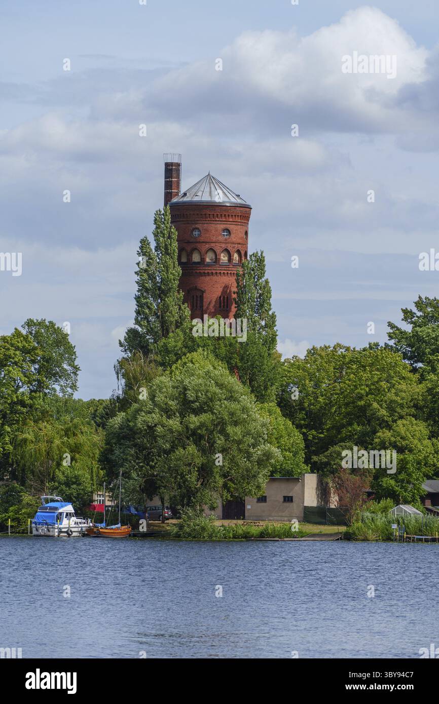 Vista dettagliata di una torre d'acqua rossa circondata da alberi su una riva del fiume, Potsdam, Brandeburgo, Germania Foto Stock