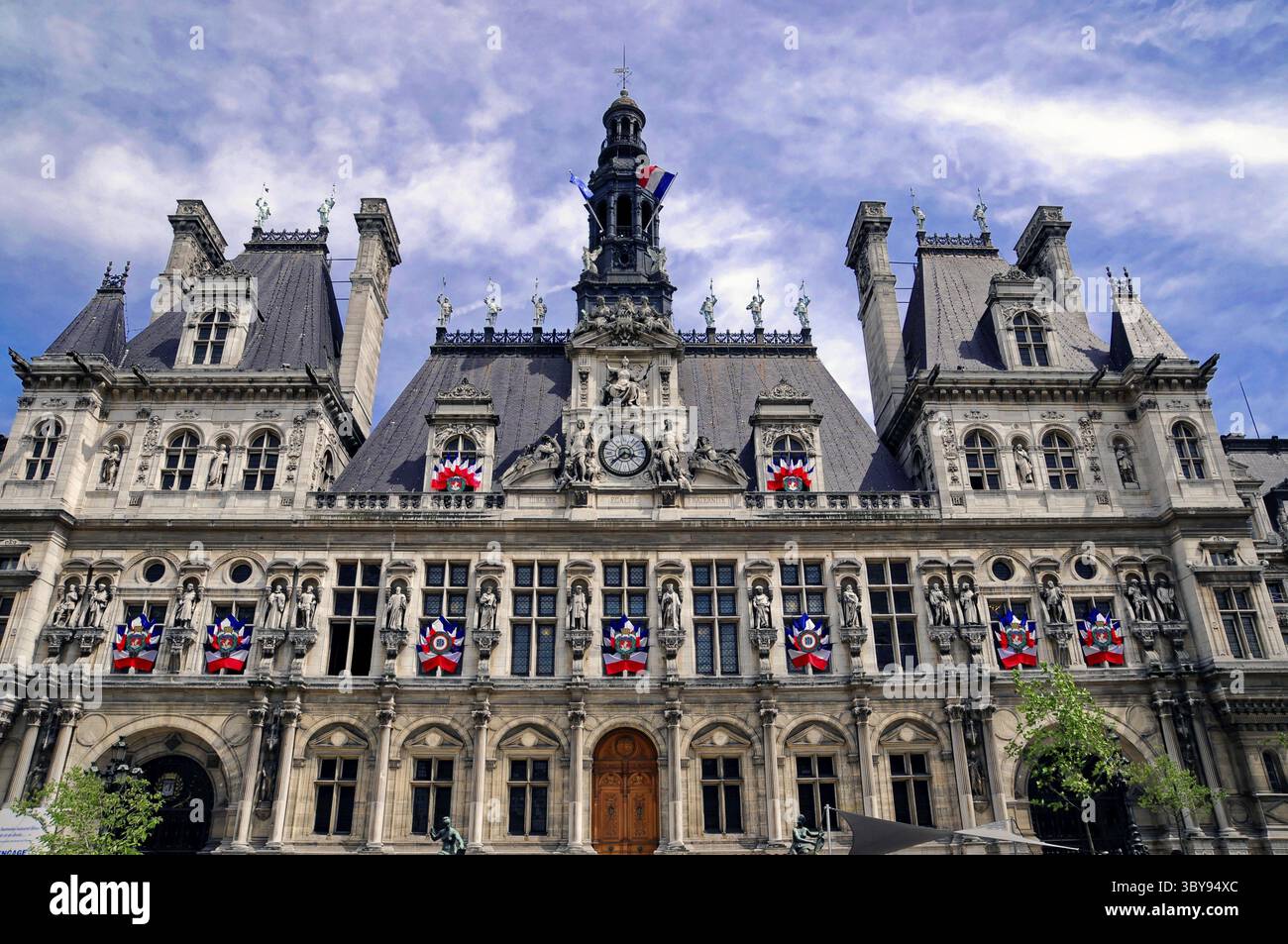City Hall, Hotel de Ville, Parigi, Francia, Europa, facciata corretta di un edificio storico con bandiere decorative sotto un cielo blu Foto Stock