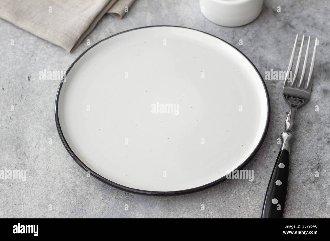 Cibo, vista dall'alto della piastra in ceramica vuota e della forchetta su sfondo in pietra grigia. Tavolo in stile rustico minimalista con tovagliolo in lino. Spazio pulito per prese alimentari Foto Stock