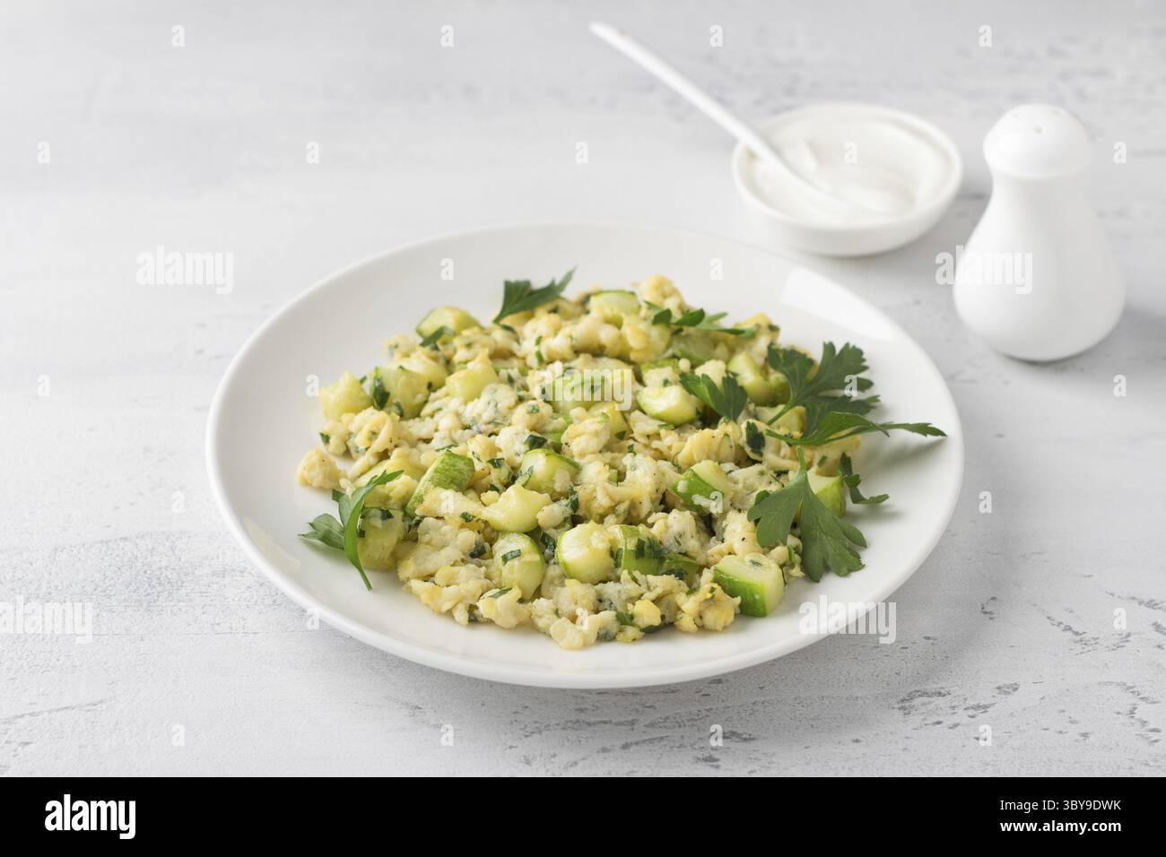 Cibo, uova strapazzate turche con zucchine servite con yogurt su sfondo azzurro. Deliziosi piatti vegetariani fatti in casa Foto Stock