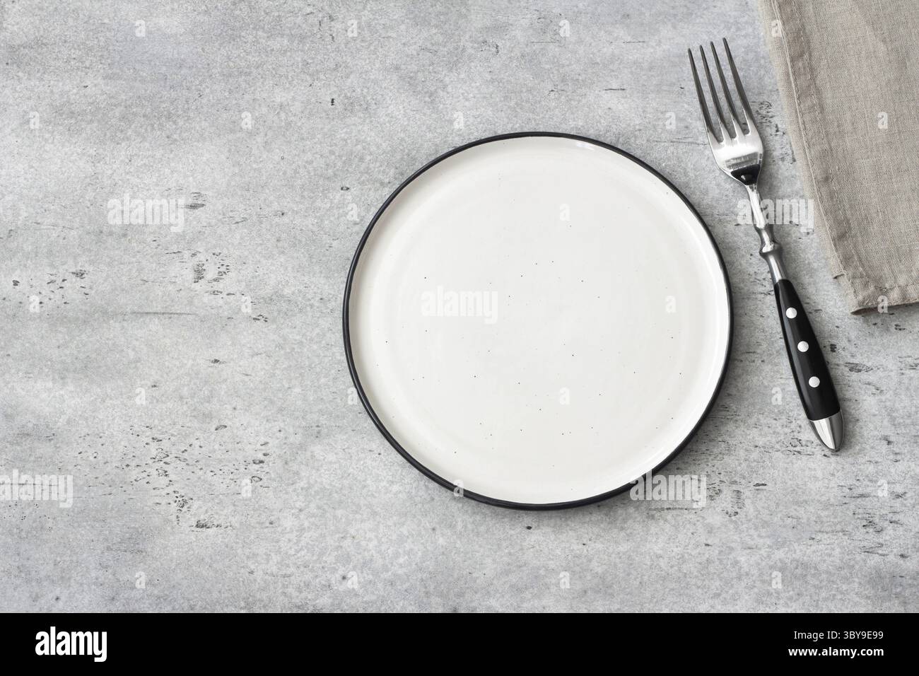 Cibo, vista dall'alto della piastra in ceramica vuota e della forchetta su sfondo in pietra grigia, spazio di copia. Tavolo in stile rustico minimalista con tovagliolo in lino. Spazio pulito per Foto Stock