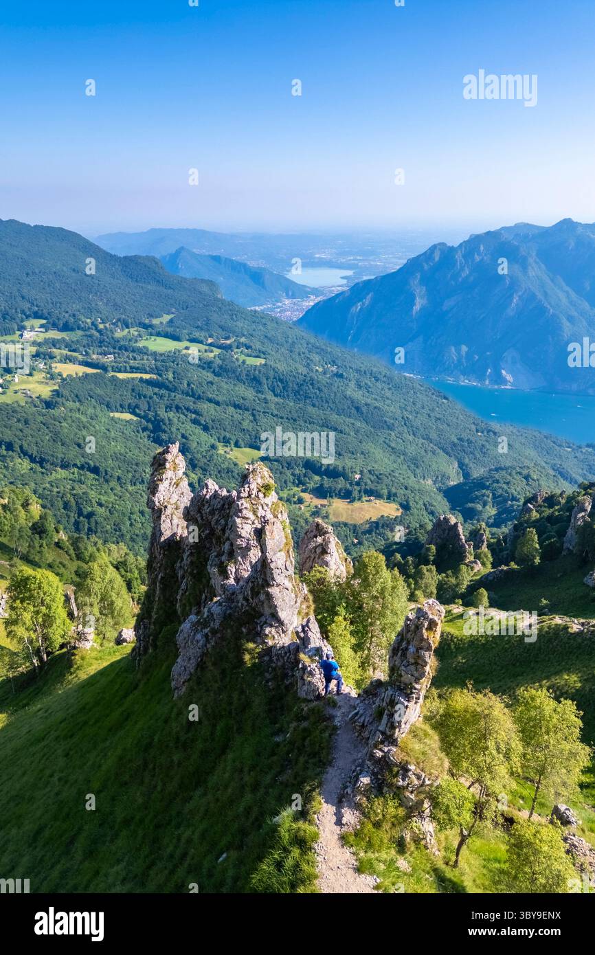 Veduta aerea di un uomo che cammina tra i pinnacoli di roccia sotto il Rifugio Rosalba. Piani Resinelli, Lecco, Lombardia, Italia. Foto Stock