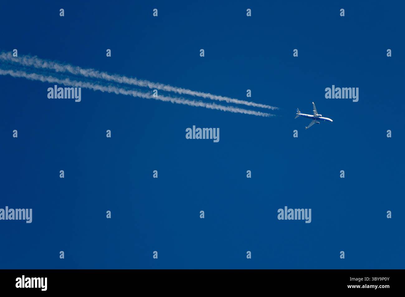 Un aereo Ryanair che vola ad alta quota contro un cielo azzurro limpido con le unghie dietro l'aereo e spazio per copiare. Foto Stock