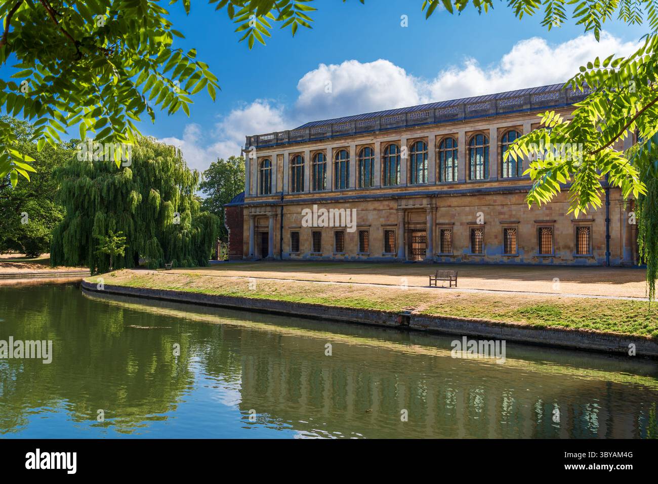 Vista frontale del Trinity College Cambridge, edificio storico sul fiume Cam con riflessi, cielo azzurro estivo e verdi salici, Inghilterra Foto Stock