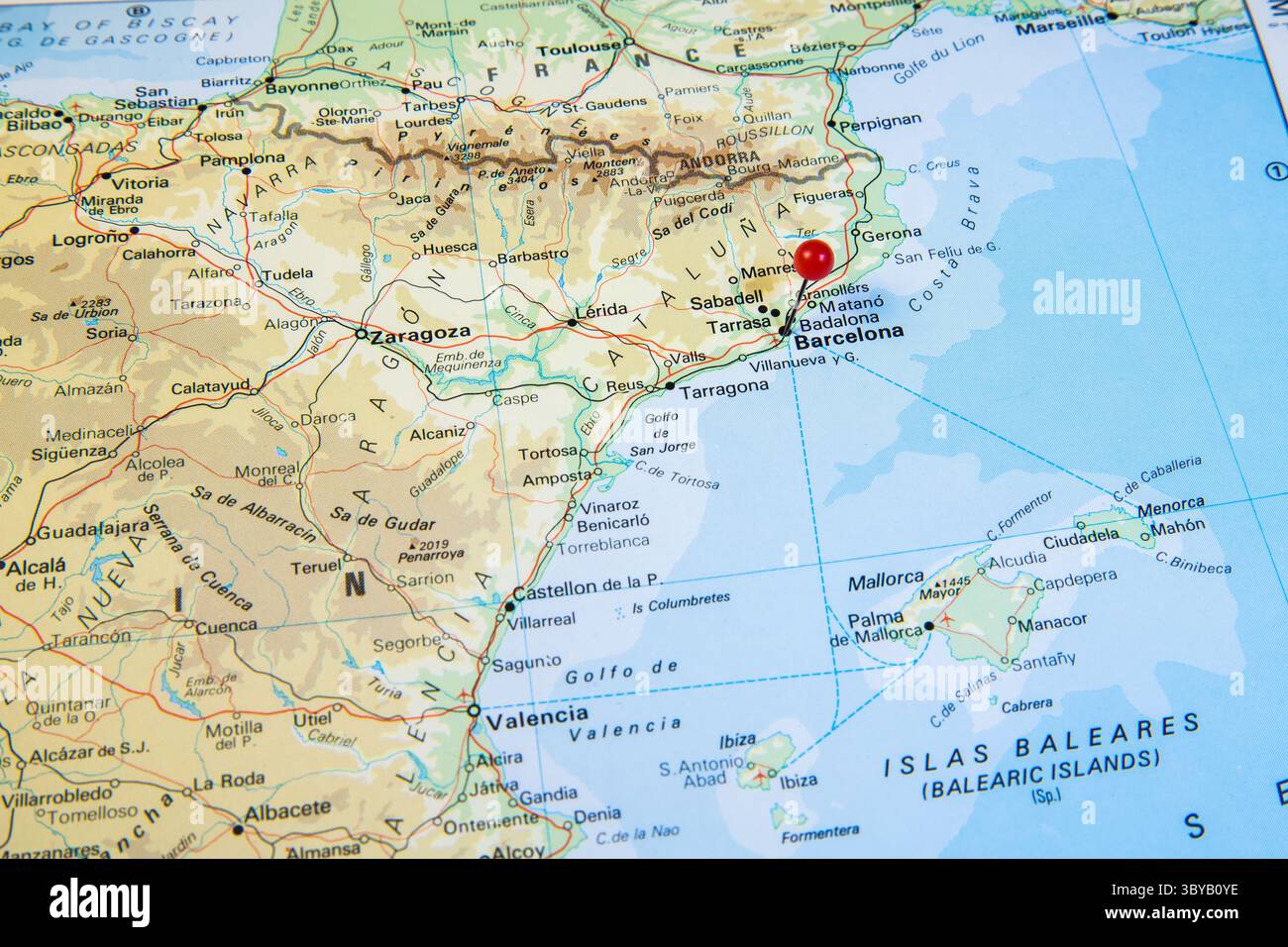 Una mappa ravvicinata della Spagna nord-orientale e della Francia meridionale con una spilla rossa che segna Barcellona, mostrando le principali città e le regioni costiere vicino alle Baleari Foto Stock