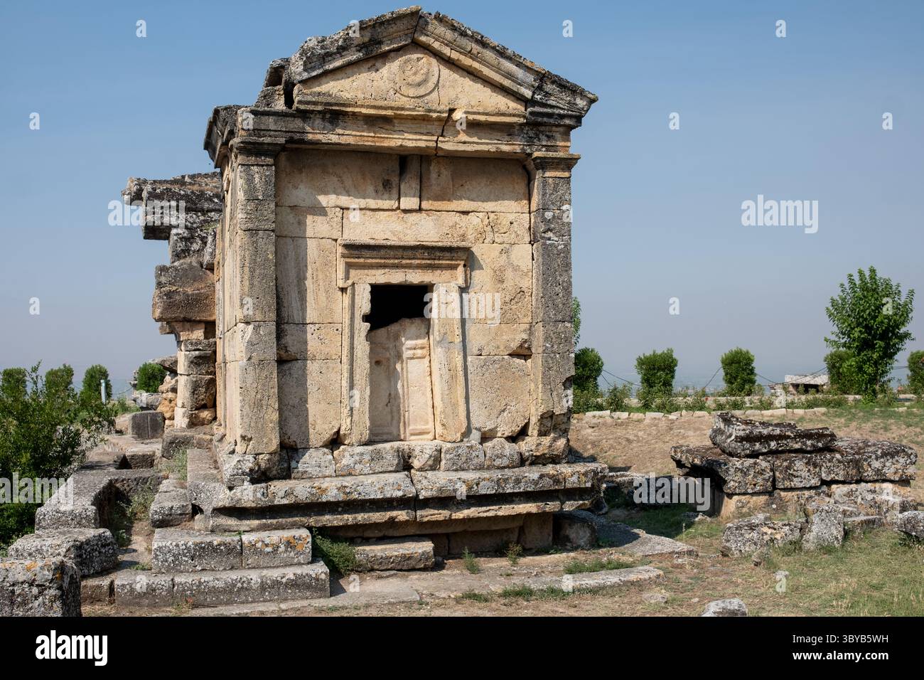 Esplora le rovine storiche di Pamukkale, evidenziando intricati lavori in pietra contro un cielo azzurro cristallino in questo notevole sito archeologico in Turchia. Foto Stock