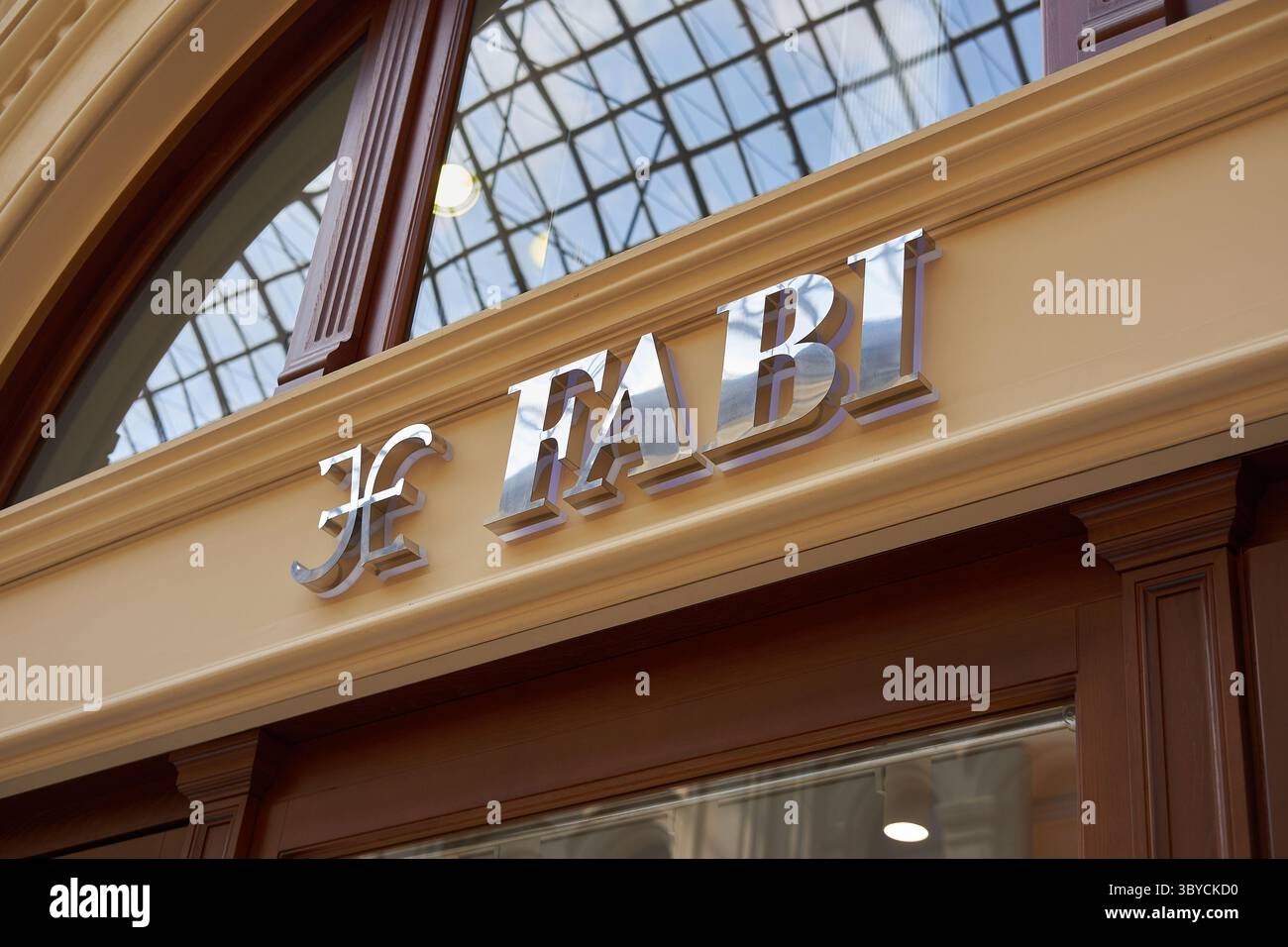 Elegante insegna FABI in lettere metallizzate montata sulla facciata classica beige sotto il soffitto ad arco in vetro Foto Stock
