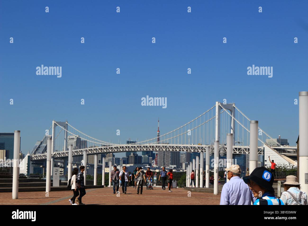 Vita quotidiana in Giappone Odaiba Promenade con vista della Tokyo Tower e del Tokyo Rainbow Bridge, con turisti che vanno e vengono Foto Stock