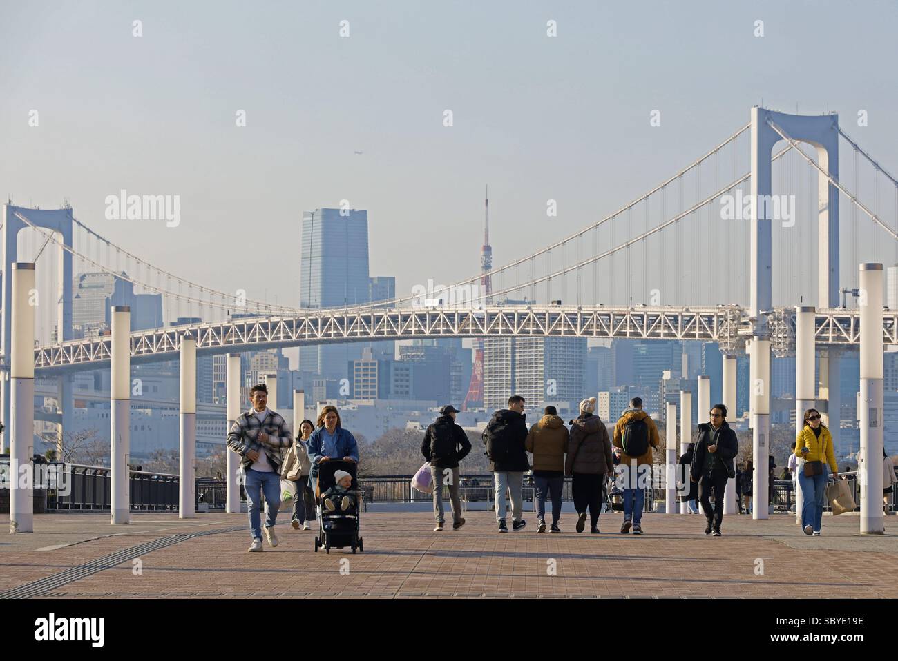 Vita quotidiana in Giappone Odaiba Promenade con vista della Tokyo Tower e del Tokyo Rainbow Bridge, con turisti che vanno e vengono Foto Stock