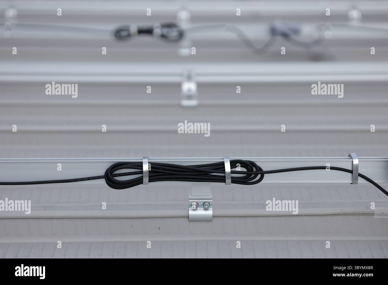 Organizzare i fili elettrici dai pannelli solari utilizzando un filo piatto di alluminio avvolto intorno alle guide. Filo di alluminio per uso esterno. Foto Stock