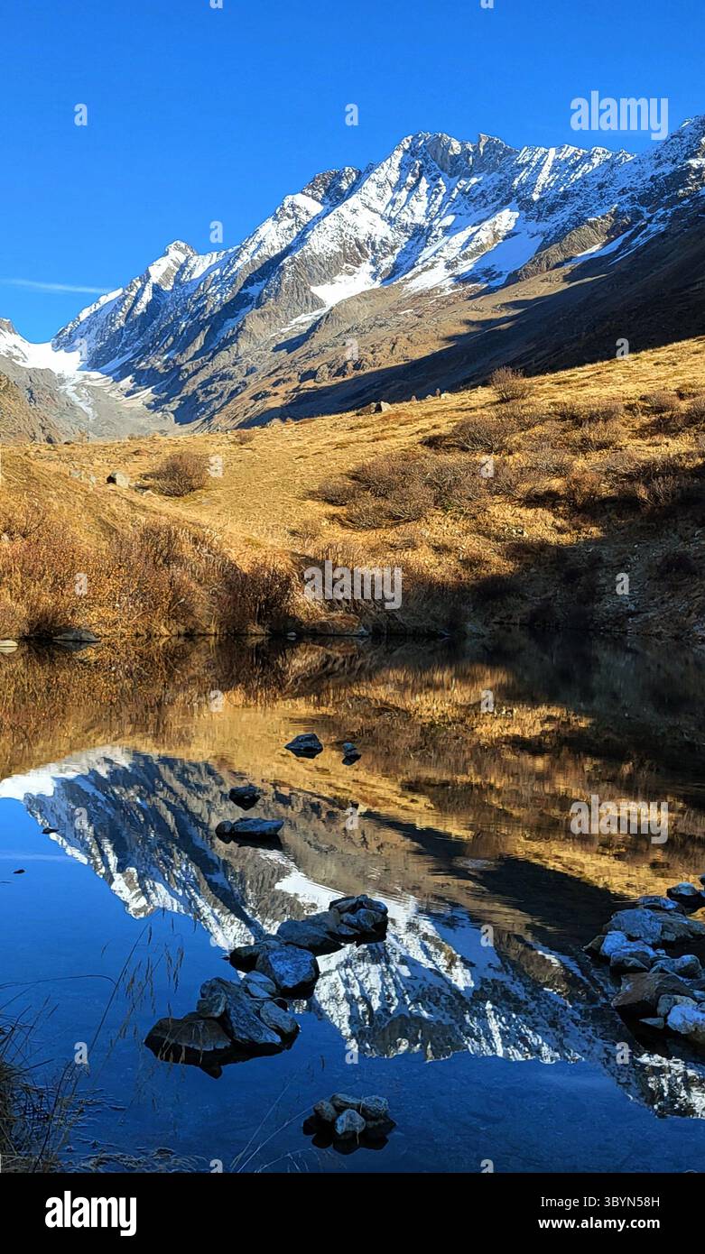Lago di montagna a Lötschental Blatten nella luce d'autunno dorata con riflesso e montagne svizzere coperte di neve Foto Stock
