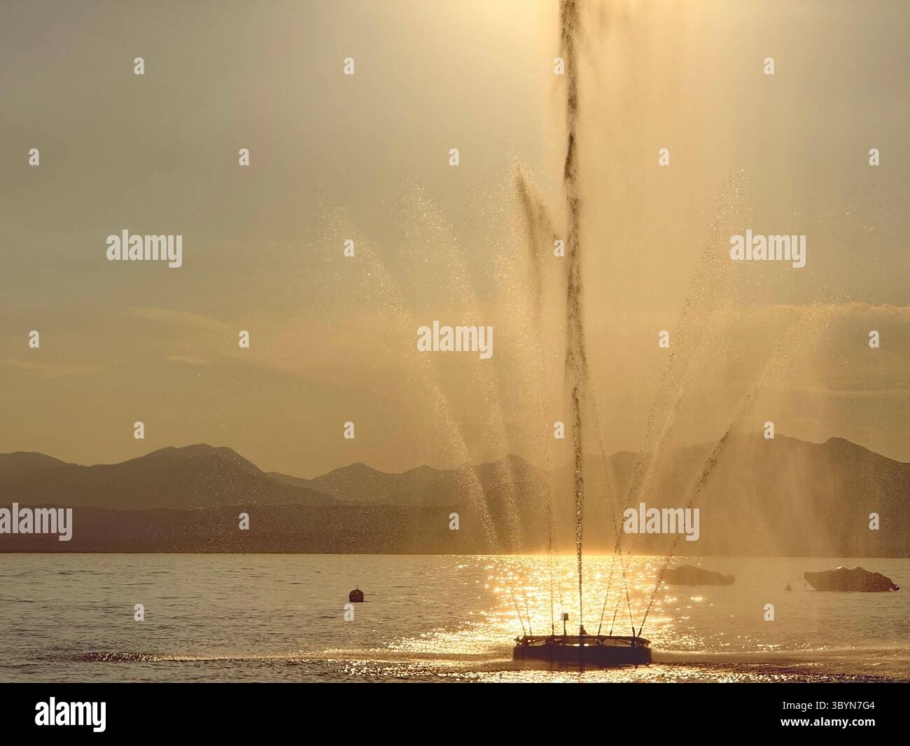 Fontana retroilluminata dal sole della tarda sera nel porto di Bardolino sul Lago di Garda, Italia Foto Stock