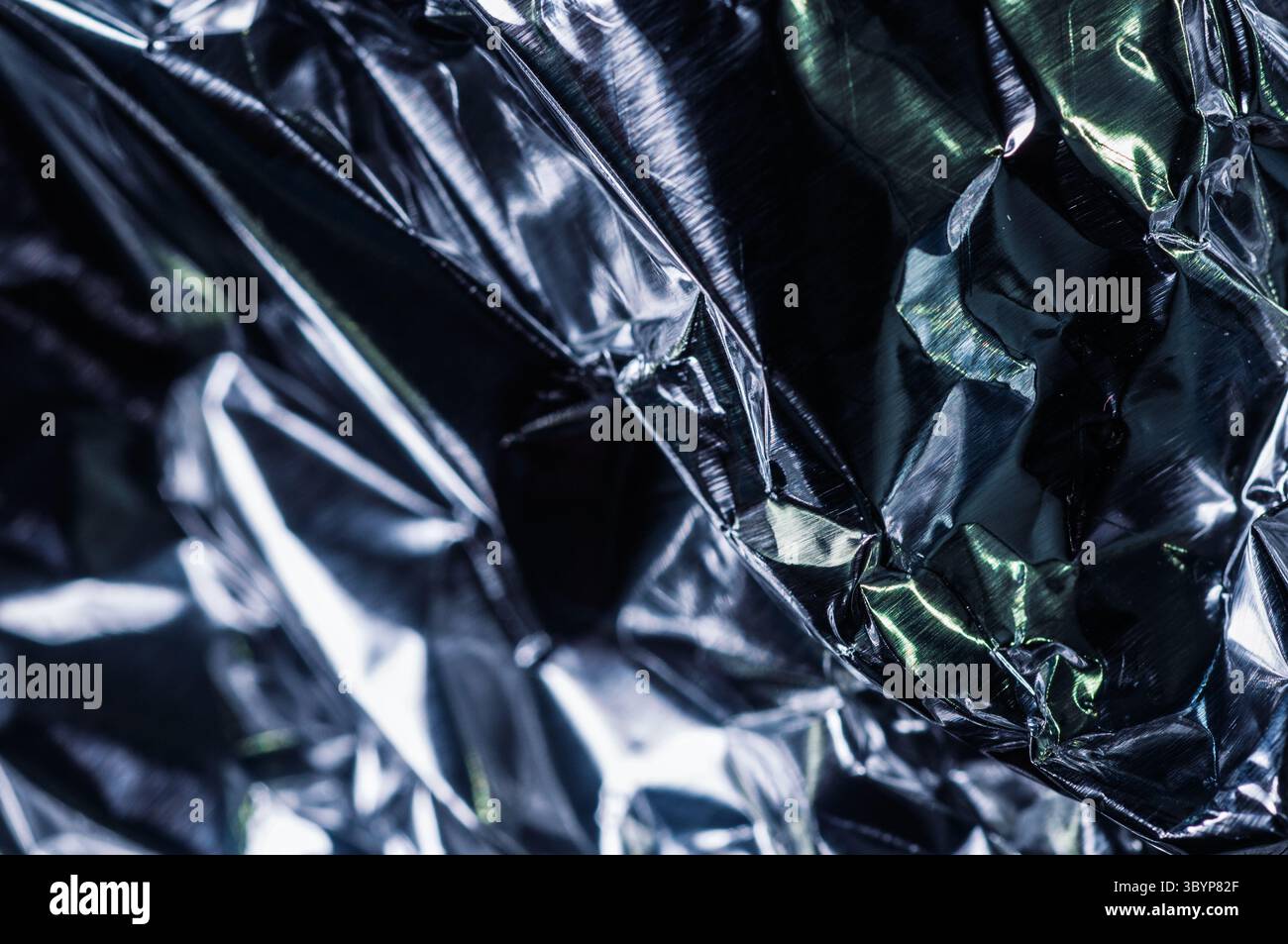Uno scatto ravvicinato rivela le pieghe intricate e la superficie riflettente della lamina d'argento increspata, catturando il gioco di luce e ombra attraverso il suo metallo Foto Stock