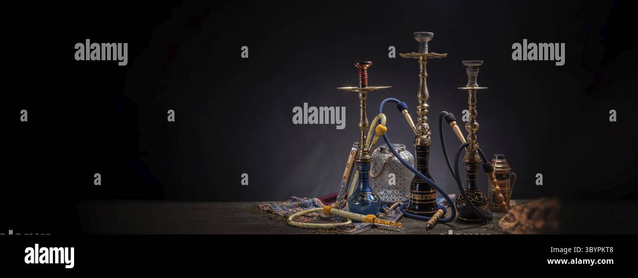 Hookah tradizionale artigianale e componenti con decorazioni rustiche, tubo di fumo d'acqua e un fazzoletto rustik sul vecchio tavolo in legno in un ro scuro moody Foto Stock