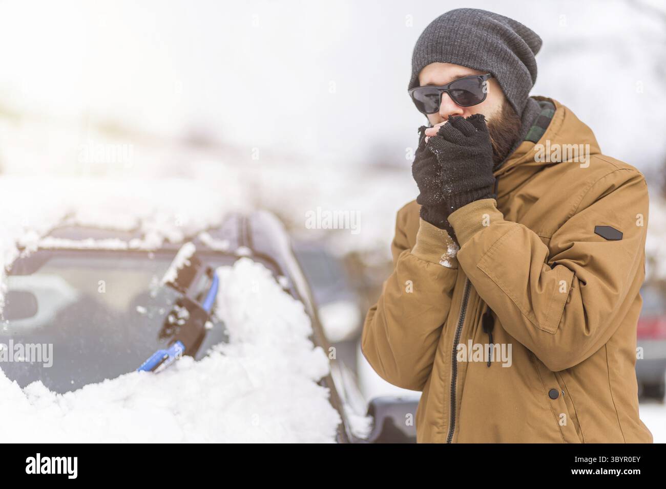 Concetto di veicolo e persone - uomo che pulisce la neve dall'auto con strumento di pulizia Foto Stock