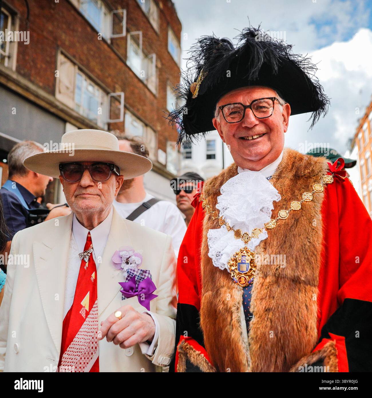 Londra, Regno Unito. 20 luglio 2025. 'Soho George', George Skeggs (a sinistra) un'istituzione Soho impeccabilmente vestita, posa con il sindaco di Westminster, Cllr Paul Dimoldenberg (a destra) nella sua vivace uniforme cerimoniale rossa alla gara. L'annuale London Waiters' Race vede ancora una volta decine di camerieri, cameriere e personale di servizio correre a piedi per le strade di Soho, tenendo in mano un vassoio con champagne e bicchieri, che deve arrivare al traguardo intatto. La gara è una tradizione di Soho che attrae londinesi e visitatori. Crediti: Imageplotter/Alamy Live News Foto Stock