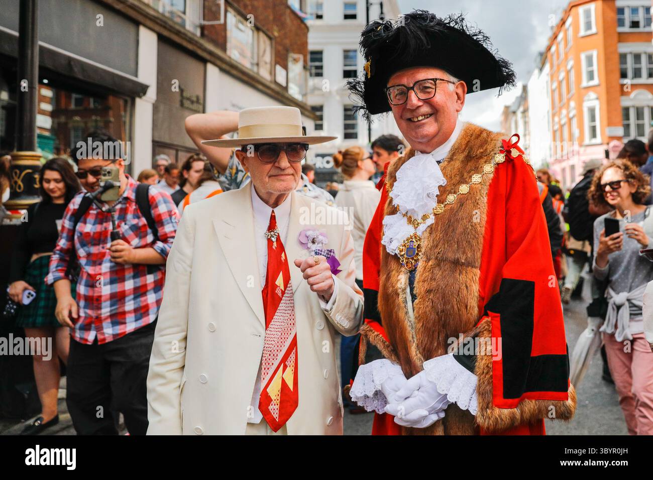 Londra, Regno Unito. 20 luglio 2025. 'Soho George', George Skeggs (a sinistra) un'istituzione Soho impeccabilmente vestita, posa con il sindaco di Westminster, Cllr Paul Dimoldenberg (a destra) nella sua vivace uniforme cerimoniale rossa alla gara. L'annuale London Waiters' Race vede ancora una volta decine di camerieri, cameriere e personale di servizio correre a piedi per le strade di Soho, tenendo in mano un vassoio con champagne e bicchieri, che deve arrivare al traguardo intatto. La gara è una tradizione di Soho che attrae londinesi e visitatori. Crediti: Imageplotter/Alamy Live News Foto Stock