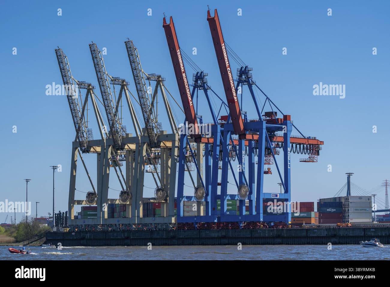 Diverse gru a cavalletto per container presso il terminale Burchardkai con caratteristiche combinazioni di colori in beige e blu-rosso, contenitori di varie spedizioni Foto Stock