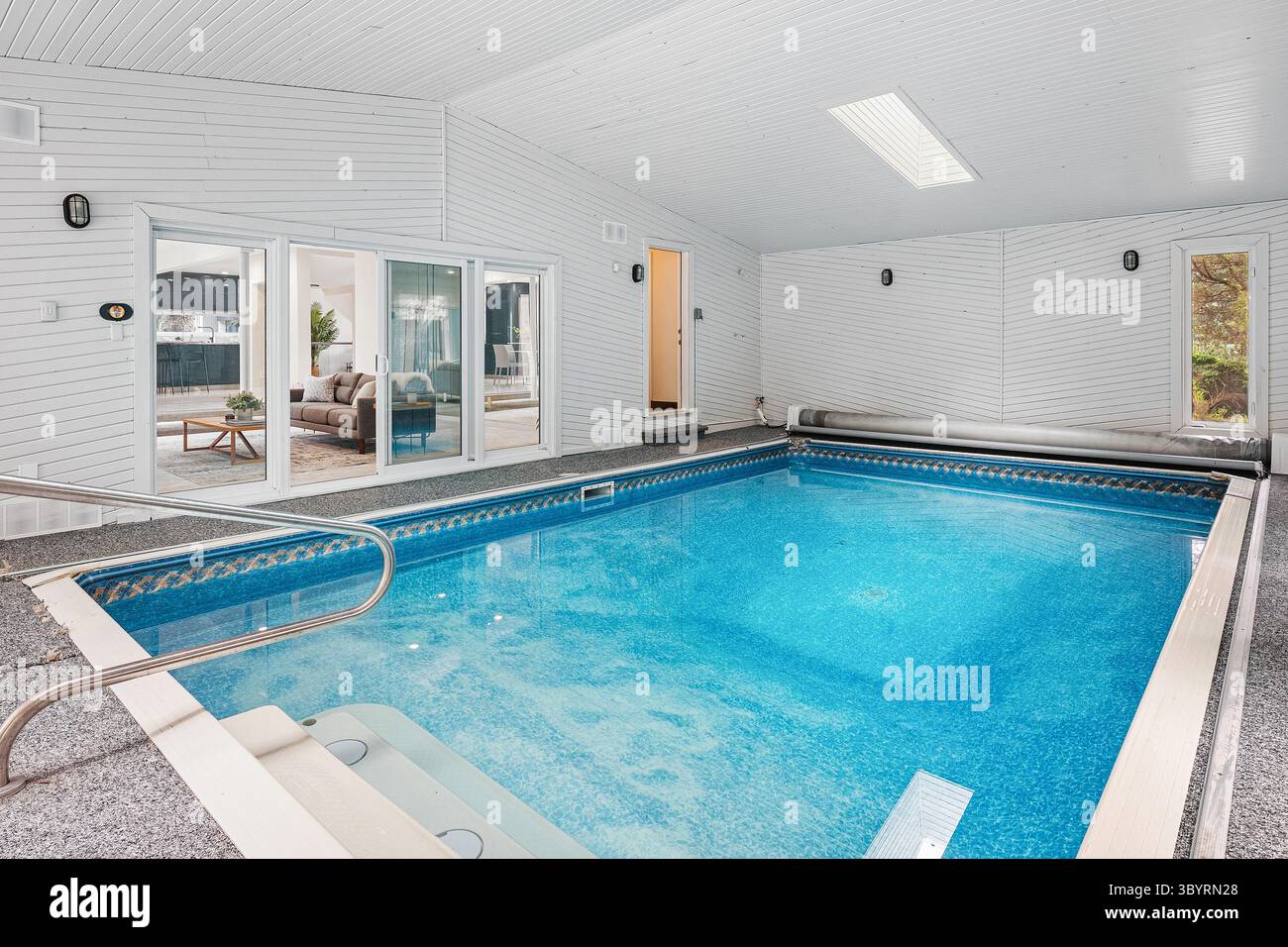 Piscina grande, pulita e pulita con soffitto bianco. La piscina è circondata da una parete bianca e ha una porta bianca. La piscina è vuota e pronta f Foto Stock