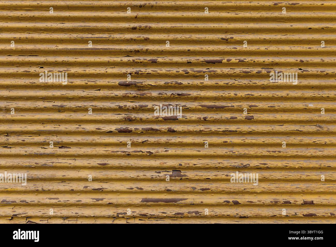 Sfondo rustico sulla strada. Vecchia porta del garage. Lamiera corrugata arrugata verniciata di giallo. Primo piano della piastra metallica ondulata Foto Stock
