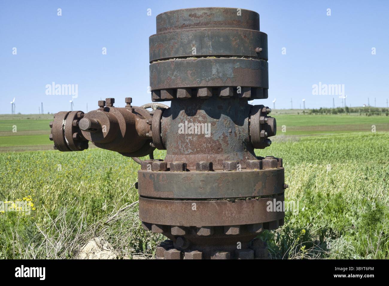 Tappare un pozzetto dell'olio, una flangia cieca. Sullo sfondo c'è una linea di turbine eoliche. La preferenza delle fonti di energia rinnovabili rispetto a quelle non rinnovabili si riduce Foto Stock