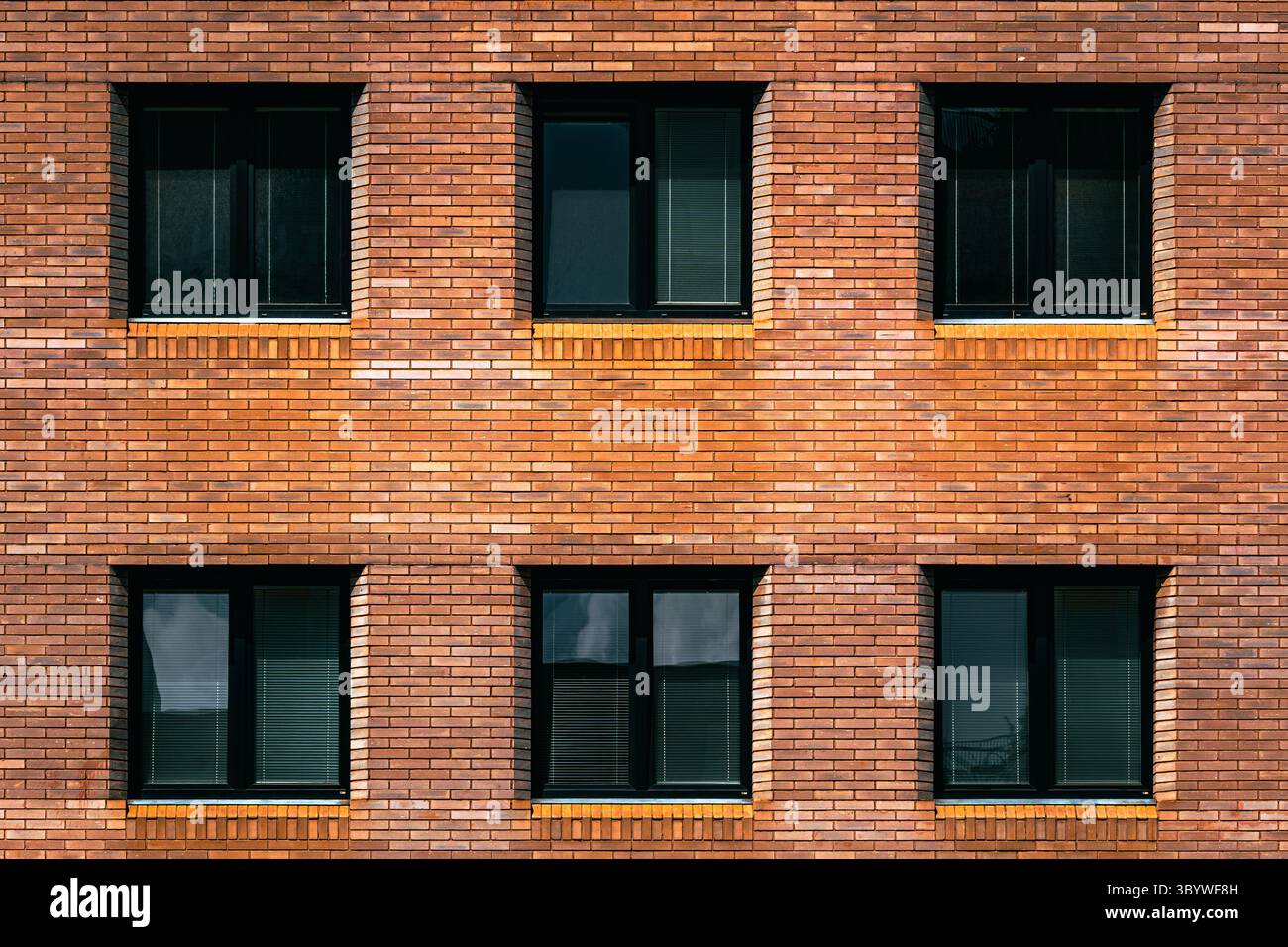 Semplici pareti in mattoni con finestre simmetriche incorniciate in nero Foto Stock
