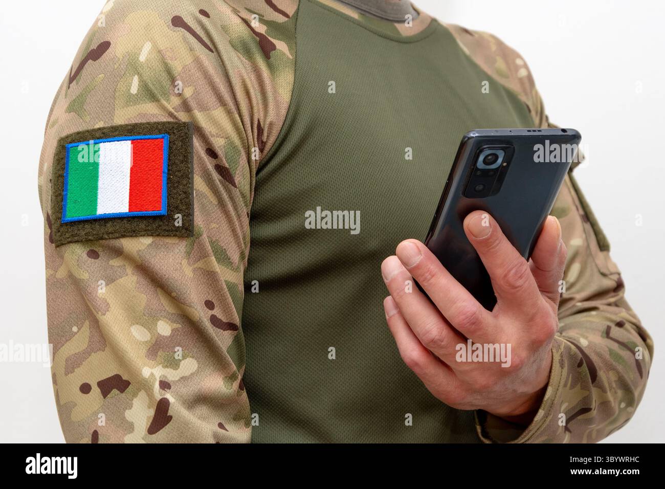 Un uomo in uniforme militare con la bandiera italiana che tiene un cellulare Foto Stock