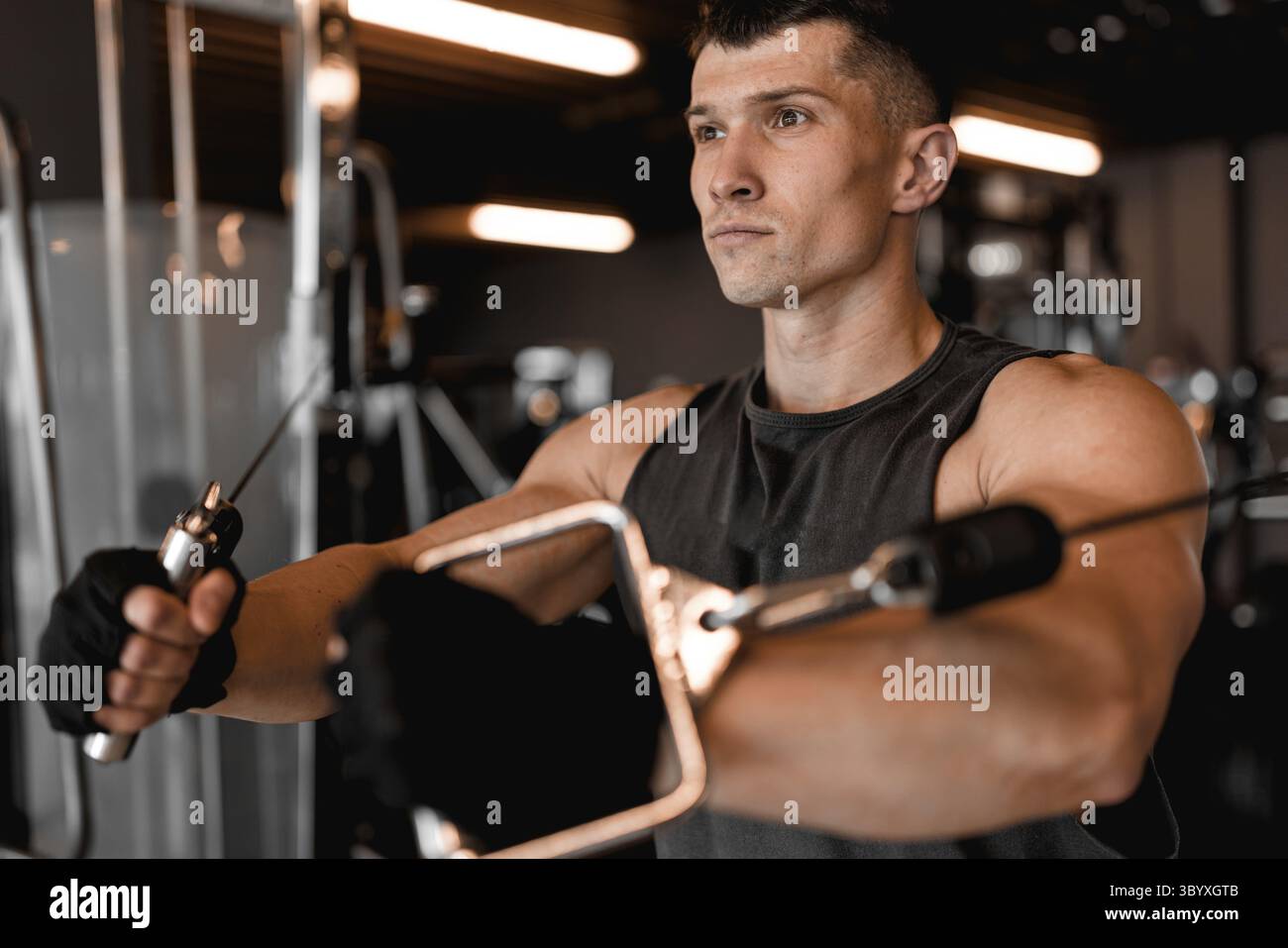 Modello maschile allenarsi in una moderna palestra con diverse attrezzature di allenamento in background Foto Stock Modello maschile allenarsi in una moderna palestra con diverse attrezzature di allenamento in background Foto Stock