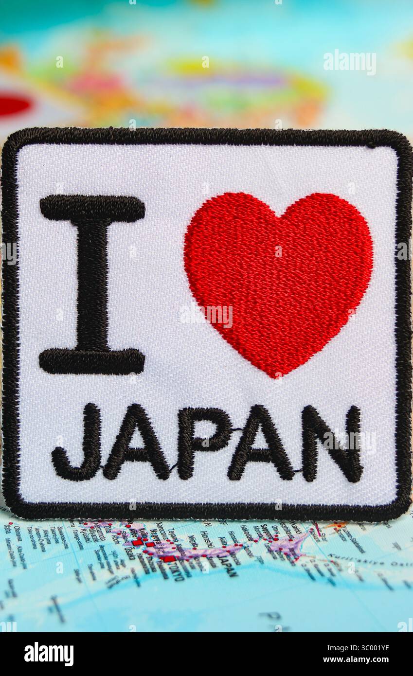 Testo ' i LOVE JAPAN ' con cuore rosso ricamato su tessuto, posizionato sulla mappa mondiale del Giappone. Simbolo dell'amore nazionale e del concetto di viaggio eco-consapevole. Foto Stock